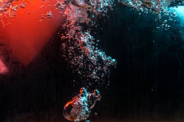 Su dokusu gürleyen kaos içinde hava kabarcıkları yaratıyor mavi ve kırmızı ışıkta dışarı kaçıyorlar.