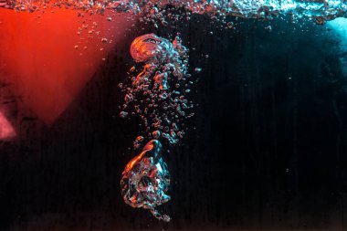 Su dokusu gürleyen kaos içinde hava kabarcıkları yaratıyor mavi ve kırmızı ışıkta dışarı kaçıyorlar.