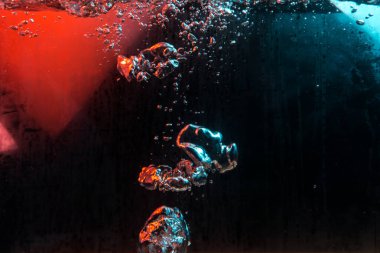 Su dokusu gürleyen kaos içinde hava kabarcıkları yaratıyor mavi ve kırmızı ışıkta dışarı kaçıyorlar.