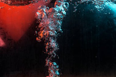 Su dokusu gürleyen kaos içinde hava kabarcıkları yaratıyor mavi ve kırmızı ışıkta dışarı kaçıyorlar.