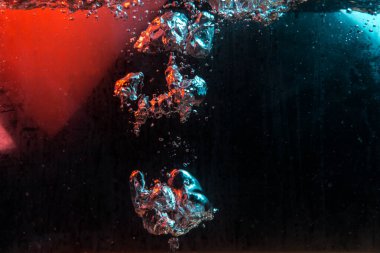 Su dokusu gürleyen kaos içinde hava kabarcıkları yaratıyor mavi ve kırmızı ışıkta dışarı kaçıyorlar.