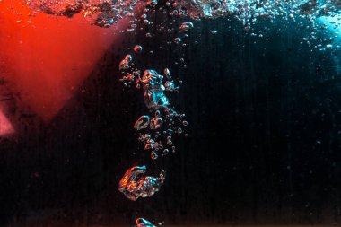 Su dokusu gürleyen kaos içinde hava kabarcıkları yaratıyor mavi ve kırmızı ışıkta dışarı kaçıyorlar.