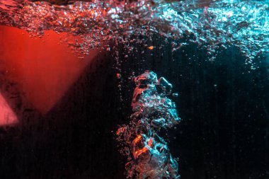 Su dokusu gürleyen kaos içinde hava kabarcıkları yaratıyor mavi ve kırmızı ışıkta dışarı kaçıyorlar.