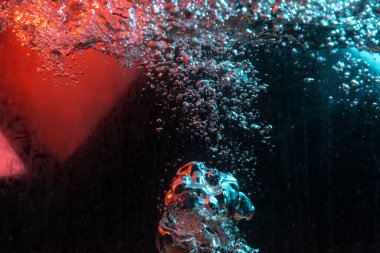 Su dokusu gürleyen kaos içinde hava kabarcıkları yaratıyor mavi ve kırmızı ışıkta dışarı kaçıyorlar.