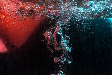 Su dokusu gürleyen kaos içinde hava kabarcıkları yaratıyor mavi ve kırmızı ışıkta dışarı kaçıyorlar.