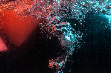 Su dokusu gürleyen kaos içinde hava kabarcıkları yaratıyor mavi ve kırmızı ışıkta dışarı kaçıyorlar.