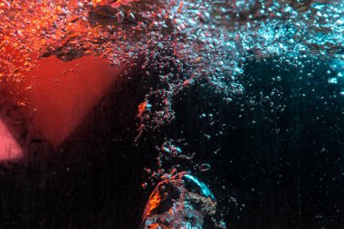 Su dokusu gürleyen kaos içinde hava kabarcıkları yaratıyor mavi ve kırmızı ışıkta dışarı kaçıyorlar.