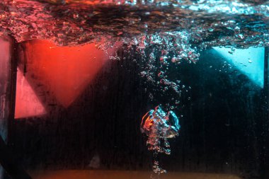 Su dokusu gürleyen kaos içinde hava kabarcıkları yaratıyor mavi ve kırmızı ışıkta dışarı kaçıyorlar.