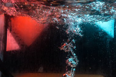 Su dokusu gürleyen kaos içinde hava kabarcıkları yaratıyor mavi ve kırmızı ışıkta dışarı kaçıyorlar.