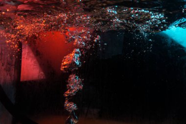 Su dokusu gürleyen kaos içinde hava kabarcıkları yaratıyor mavi ve kırmızı ışıkta dışarı kaçıyorlar.