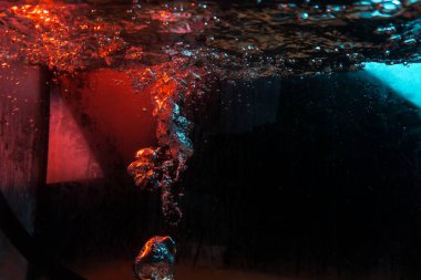 Su dokusu gürleyen kaos içinde hava kabarcıkları yaratıyor mavi ve kırmızı ışıkta dışarı kaçıyorlar.