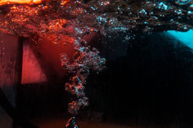 Su dokusu gürleyen kaos içinde hava kabarcıkları yaratıyor mavi ve kırmızı ışıkta dışarı kaçıyorlar.