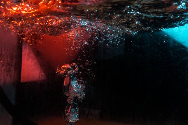 Su dokusu gürleyen kaos içinde hava kabarcıkları yaratıyor mavi ve kırmızı ışıkta dışarı kaçıyorlar.