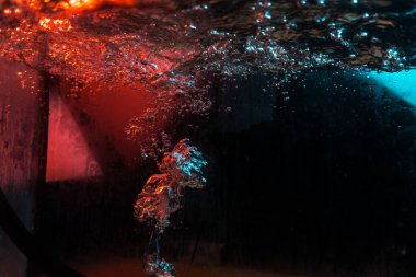 Su dokusu gürleyen kaos içinde hava kabarcıkları yaratıyor mavi ve kırmızı ışıkta dışarı kaçıyorlar.