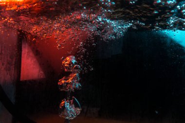 Su dokusu gürleyen kaos içinde hava kabarcıkları yaratıyor mavi ve kırmızı ışıkta dışarı kaçıyorlar.