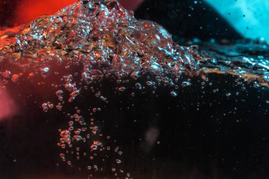 Su dokusu gürleyen kaos içinde hava kabarcıkları yaratıyor mavi ve kırmızı ışıkta dışarı kaçıyorlar.