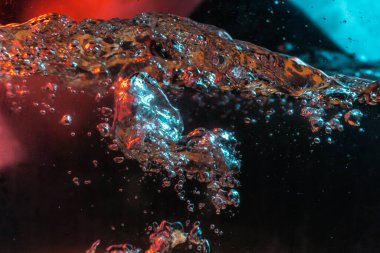 Su dokusu gürleyen kaos içinde hava kabarcıkları yaratıyor mavi ve kırmızı ışıkta dışarı kaçıyorlar.