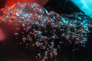 Su dokusu gürleyen kaos içinde hava kabarcıkları yaratıyor mavi ve kırmızı ışıkta dışarı kaçıyorlar.