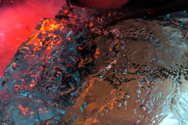 Su dokusu gürleyen kaos içinde hava kabarcıkları yaratıyor mavi ve kırmızı ışıkta dışarı kaçıyorlar.