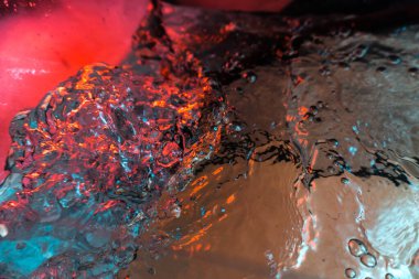 Su dokusu gürleyen kaos içinde hava kabarcıkları yaratıyor mavi ve kırmızı ışıkta dışarı kaçıyorlar.