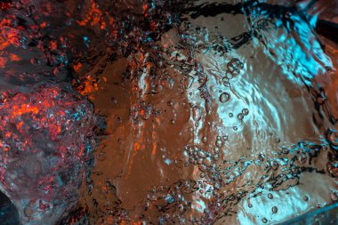 Su dokusu gürleyen kaos içinde hava kabarcıkları yaratıyor mavi ve kırmızı ışıkta dışarı kaçıyorlar.