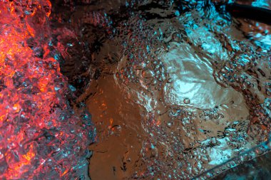 Su dokusu gürleyen kaos içinde hava kabarcıkları yaratıyor mavi ve kırmızı ışıkta dışarı kaçıyorlar.