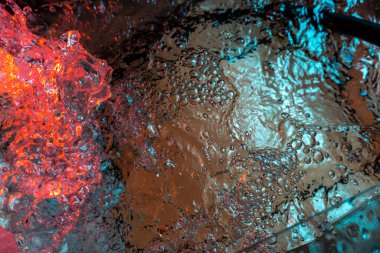 Su dokusu gürleyen kaos içinde hava kabarcıkları yaratıyor mavi ve kırmızı ışıkta dışarı kaçıyorlar.