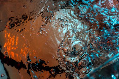 Su dokusu gürleyen kaos içinde hava kabarcıkları yaratıyor mavi ve kırmızı ışıkta dışarı kaçıyorlar.