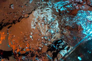 Su dokusu gürleyen kaos içinde hava kabarcıkları yaratıyor mavi ve kırmızı ışıkta dışarı kaçıyorlar.