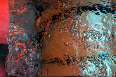 Su dokusu gürleyen kaos içinde hava kabarcıkları yaratıyor mavi ve kırmızı ışıkta dışarı kaçıyorlar.