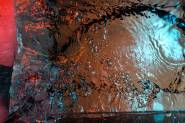 Su dokusu gürleyen kaos içinde hava kabarcıkları yaratıyor mavi ve kırmızı ışıkta dışarı kaçıyorlar.