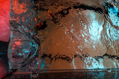 Su dokusu gürleyen kaos içinde hava kabarcıkları yaratıyor mavi ve kırmızı ışıkta dışarı kaçıyorlar.