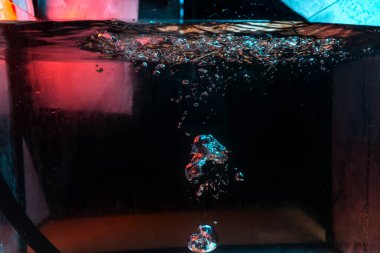 Su dokusu gürleyen kaos içinde hava kabarcıkları yaratıyor mavi ve kırmızı ışıkta dışarı kaçıyorlar.