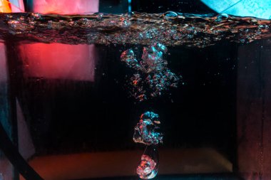 Su dokusu gürleyen kaos içinde hava kabarcıkları yaratıyor mavi ve kırmızı ışıkta dışarı kaçıyorlar.