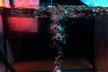 Su dokusu gürleyen kaos içinde hava kabarcıkları yaratıyor mavi ve kırmızı ışıkta dışarı kaçıyorlar.