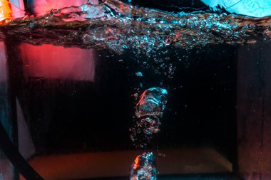 Su dokusu gürleyen kaos içinde hava kabarcıkları yaratıyor mavi ve kırmızı ışıkta dışarı kaçıyorlar.