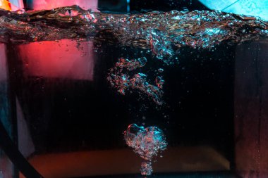 Su dokusu gürleyen kaos içinde hava kabarcıkları yaratıyor mavi ve kırmızı ışıkta dışarı kaçıyorlar.