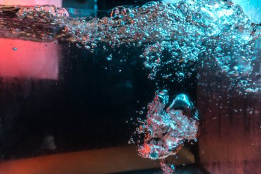 Su dokusu gürleyen kaos içinde hava kabarcıkları yaratıyor mavi ve kırmızı ışıkta dışarı kaçıyorlar.