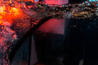 Su dokusu gürleyen kaos içinde hava kabarcıkları yaratıyor mavi ve kırmızı ışıkta dışarı kaçıyorlar.