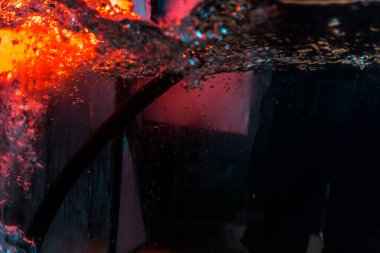 Su dokusu gürleyen kaos içinde hava kabarcıkları yaratıyor mavi ve kırmızı ışıkta dışarı kaçıyorlar.