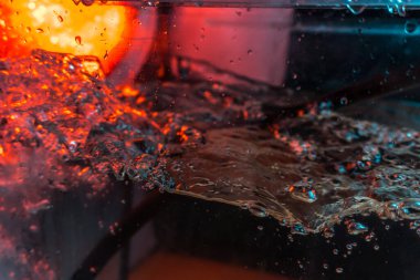 Bir volkanın lavında denizin taklidi, suyun dokusu kırmızı ışıkta çıkan hava kabarcıklarıyla kaos yaratıyor.