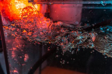 Bir volkanın lavında denizin taklidi, suyun dokusu kırmızı ışıkta çıkan hava kabarcıklarıyla kaos yaratıyor.