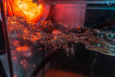 Bir volkanın lavında denizin taklidi, suyun dokusu kırmızı ışıkta çıkan hava kabarcıklarıyla kaos yaratıyor.