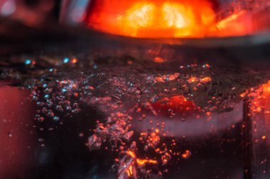 Bir volkanın lavında denizin taklidi, suyun dokusu kırmızı ışıkta çıkan hava kabarcıklarıyla kaos yaratıyor.