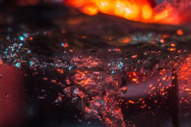 Bir volkanın lavında denizin taklidi, suyun dokusu kırmızı ışıkta çıkan hava kabarcıklarıyla kaos yaratıyor.