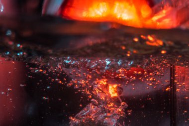 Bir volkanın lavında denizin taklidi, suyun dokusu kırmızı ışıkta çıkan hava kabarcıklarıyla kaos yaratıyor.