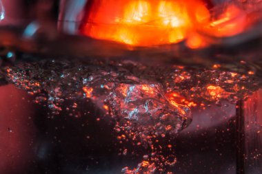 Bir volkanın lavında denizin taklidi, suyun dokusu kırmızı ışıkta çıkan hava kabarcıklarıyla kaos yaratıyor.