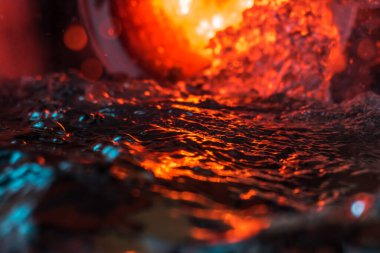 Bir volkanın lavında denizin taklidi, suyun dokusu kırmızı ışıkta çıkan hava kabarcıklarıyla kaos yaratıyor.