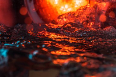 Bir volkanın lavında denizin taklidi, suyun dokusu kırmızı ışıkta çıkan hava kabarcıklarıyla kaos yaratıyor.