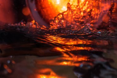 Bir volkanın lavında denizin taklidi, suyun dokusu kırmızı ışıkta çıkan hava kabarcıklarıyla kaos yaratıyor.